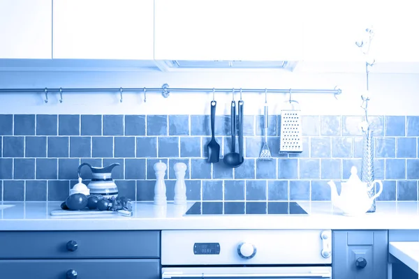 Кухня має темно-сірі плоскі передні шафи в парі з білими кварцовими стільницями і глянсовою синьою плиткою для догляду . — стокове фото