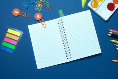 Mavi arka plan üzerinde renkli kalemler makas ile yuvarlak çerçeve, okul kavramına geri