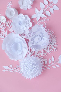Pembe arka planda beyaz kağıt çiçekler. Kağıttan kesme.