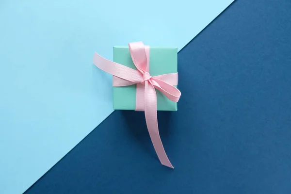 Regalo azul atado con cinta rosa sobre fondo azul — Foto de Stock