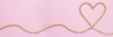 Pembe arka planda kalp şeklinde altın bir zincir serilmiş.