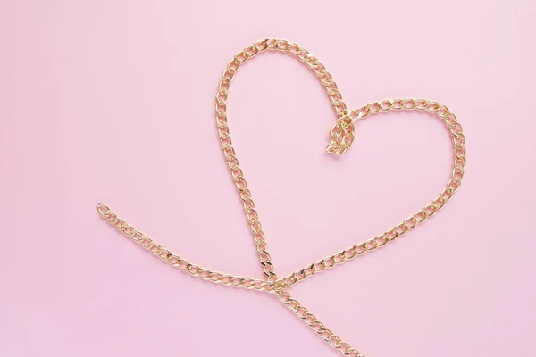 Een gouden ketting in de vorm van een hart op een roze achtergrond — Stockfoto