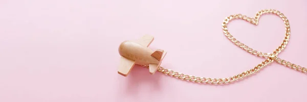 Klein houten speelgoedvliegtuigje draagt in de vorm van een hart uit een gouden ketting — Stockfoto