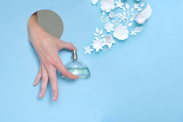 Bir kadının eli delikten dışarı bakar ve bir şişe parfüm tutar.