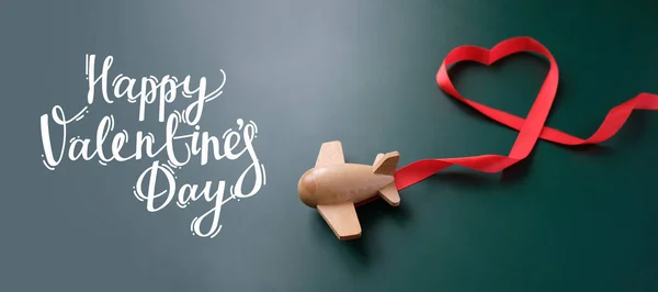 Pequeño avión de juguete de madera con suerte con cinta roja en forma de corazón — Foto de Stock