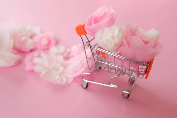 Merhaba bahar. Beyaz, pembe kağıt çiçekler ve yeşil yapraklı alışveriş arabası.