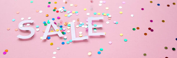 Продажа с красочными конфетти на розовом фоне
