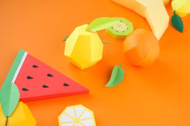 Turuncu arka planda kağıttan farklı egzotik meyveler.