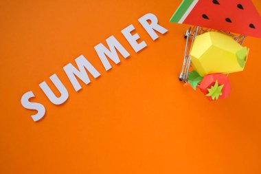 Turuncu arka planda kağıttan farklı egzotik meyveler.