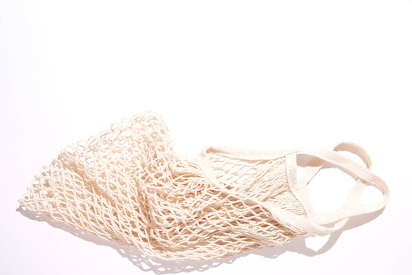 Empty reusable shopping string bag on white with shadow. Zero waste concept. View from above.