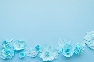Delicate blue paper flowers on blue background. Summer concept