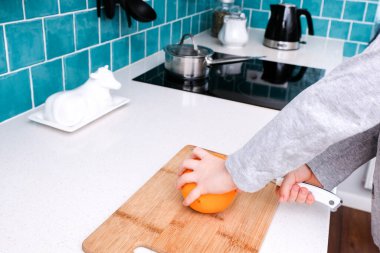 Bebeğin elleri mutfaktaki kesme tahtasıyla portakal kesti.