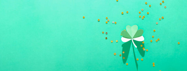 St. Patrick's day, pattern of clovers cut out of paper on a green shiny background