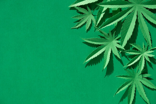 Лист конопли, вырезанный из бумаги на зеленом фоне. Символ
.