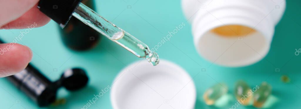 Essential oil falling from glass dropper. Fish oil capsules on a blue background. Beriberi, strengthening the immune system