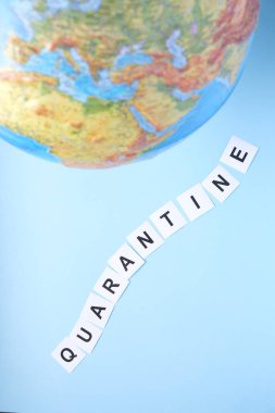 Dünya çapında karantina kavramı. Küre ve mavi arka planda karantina kelimesi