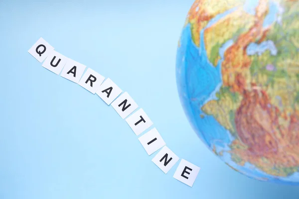 The concept of a worldwide quarantine. Globe and the word quarantine on a blue background