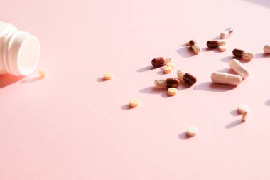 Pembe arka planda çeşitli ilaç hapları, haplar ve kapsüller var. Kavram salgını, koronavirüs 2019