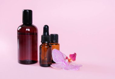 Temel yağlar, pembe arka planda farklı şişeler. Aromaterapi kavramı. Sağlığın korunması, doğal tedaviler..
