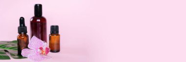 Temel yağlar, pembe arka planda farklı şişeler. Aromaterapi kavramı. Sağlığın korunması, doğal tedaviler..