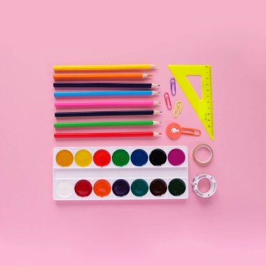 Pembe arka planda kırtasiye malzemesi, üstünde ev şeklinde kırtasiye malzemesi. Ev eğitimi kavramı