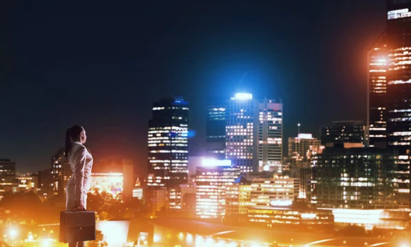 Женщина смотрит на ночной город — стоковое фото