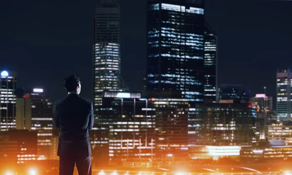 Affärsman som tittar på natten glödande city — Stockfoto