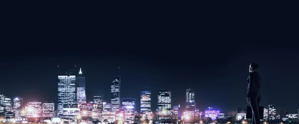 Zakenvrouw die nacht gloeiende city bekeken — Stockfoto