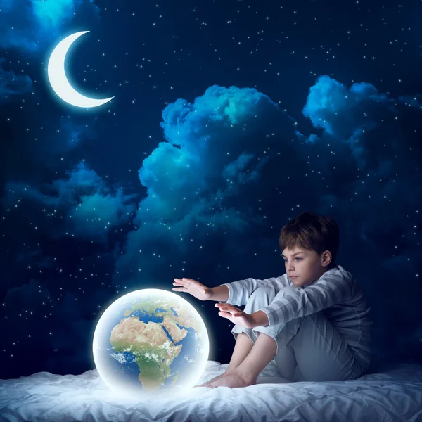 Boy in bed looking at glowing Earth — Stock Photo, Image