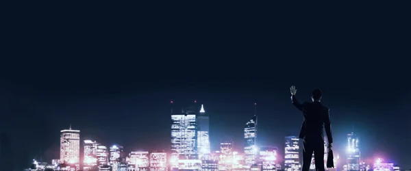 Бізнесмен дивиться нічне сяюче місто — стокове фото