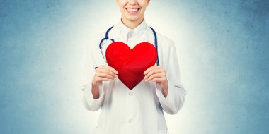 Kırmızı kalp tutan genç kadın doktor