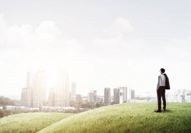 Tepenin üstünde duran işadamı 