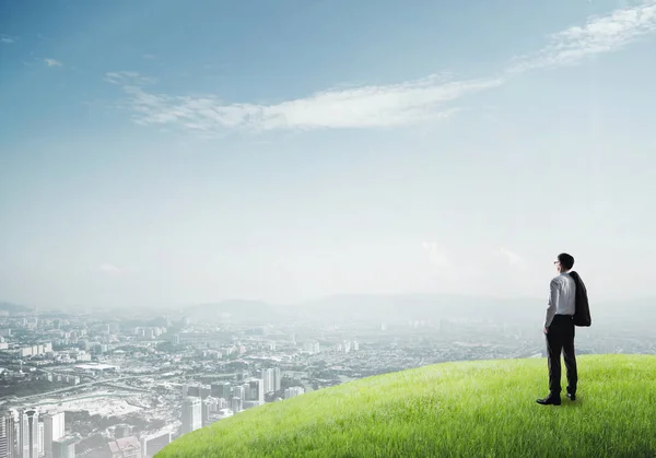 Бизнесмен, стоящий на вершине холма — стоковое фото