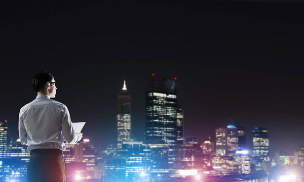 businessman with suitcase looking at night city