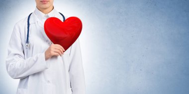 Kırmızı kalp tutan genç kadın doktor