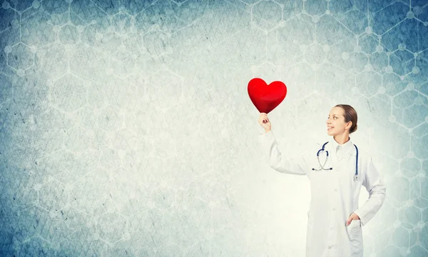 Νεαρή γυναίκα ο γιατρός κρατάει κόκκινη καρδιά — Φωτογραφία Αρχείου