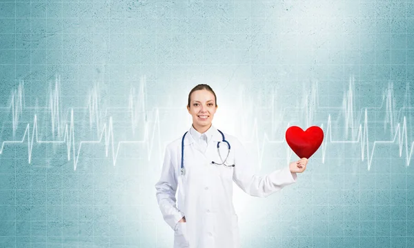 Kırmızı kalp tutan genç kadın doktor — Stok fotoğraf