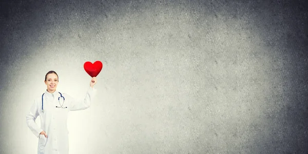 Doktor mladá žena držící červené srdce — Stock fotografie