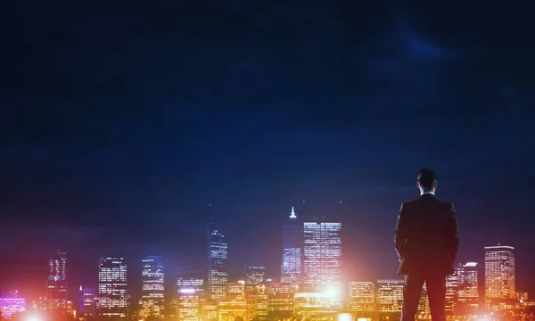Homme d'affaires regardant nuit ville rayonnante — Photo