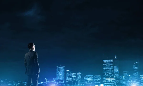 Affärsman som tittar på natten glödande city — Stockfoto