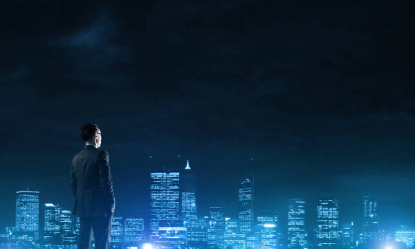 Elegant businessman with suitcase looking at night city