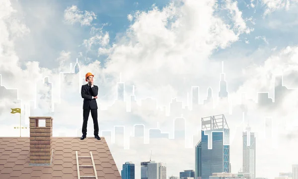 Affärsman i kostym och hjälm på takkanten — Stockfoto