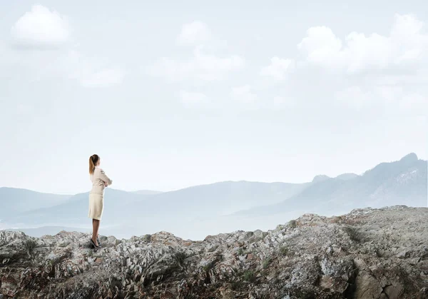 Элегантная деловая женщина, стоящая на скале — стоковое фото