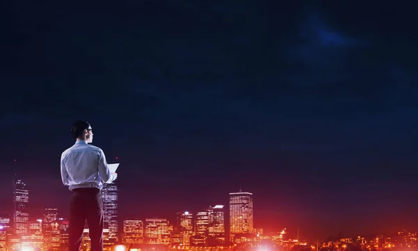 Homme d'affaires regardant nuit ville rayonnante — Photo