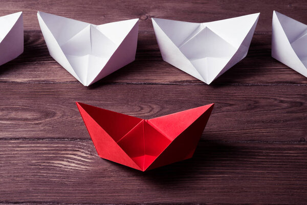 Business leadership concept with white and color paper boats on 