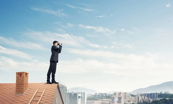 Hombre de negocios de pie en el techo de casa — Foto de Stock