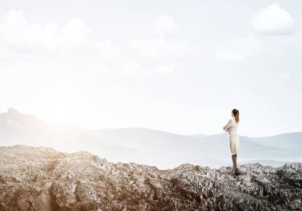 Elegant businesswoman standing on rock 