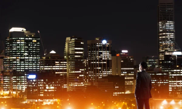 Zakenman die nacht gloeiende city bekeken — Stockfoto