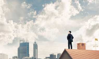 evin çatısında duran işadamı 