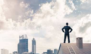 evin çatısında duran işadamı 